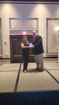 Zaida Gonzalez is handed a plaque by a representative of the Florida Association of Community Agencies