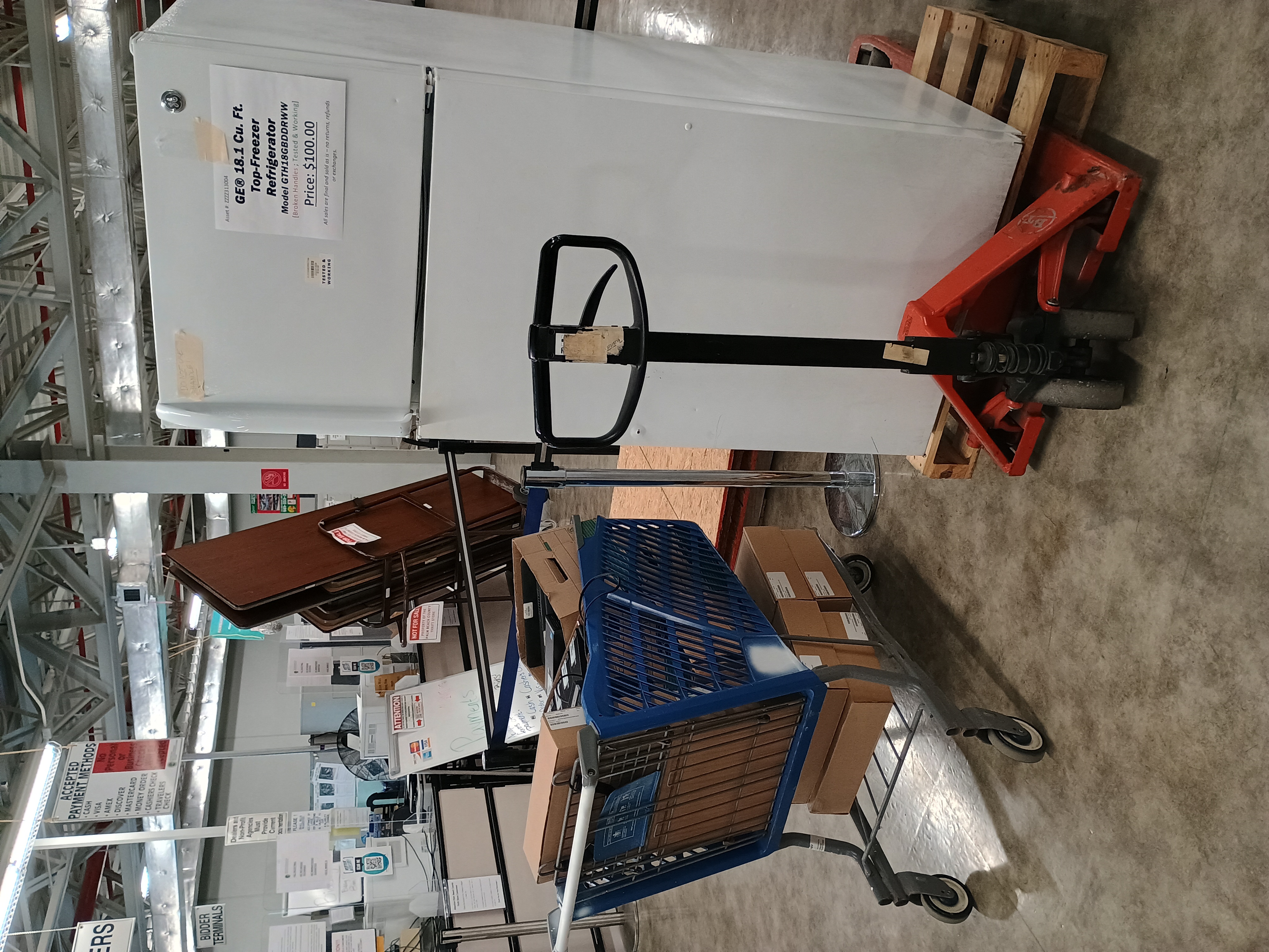 Blue shopping cart filled with broken computers and laptops, White refrigerator on pallet.jpg