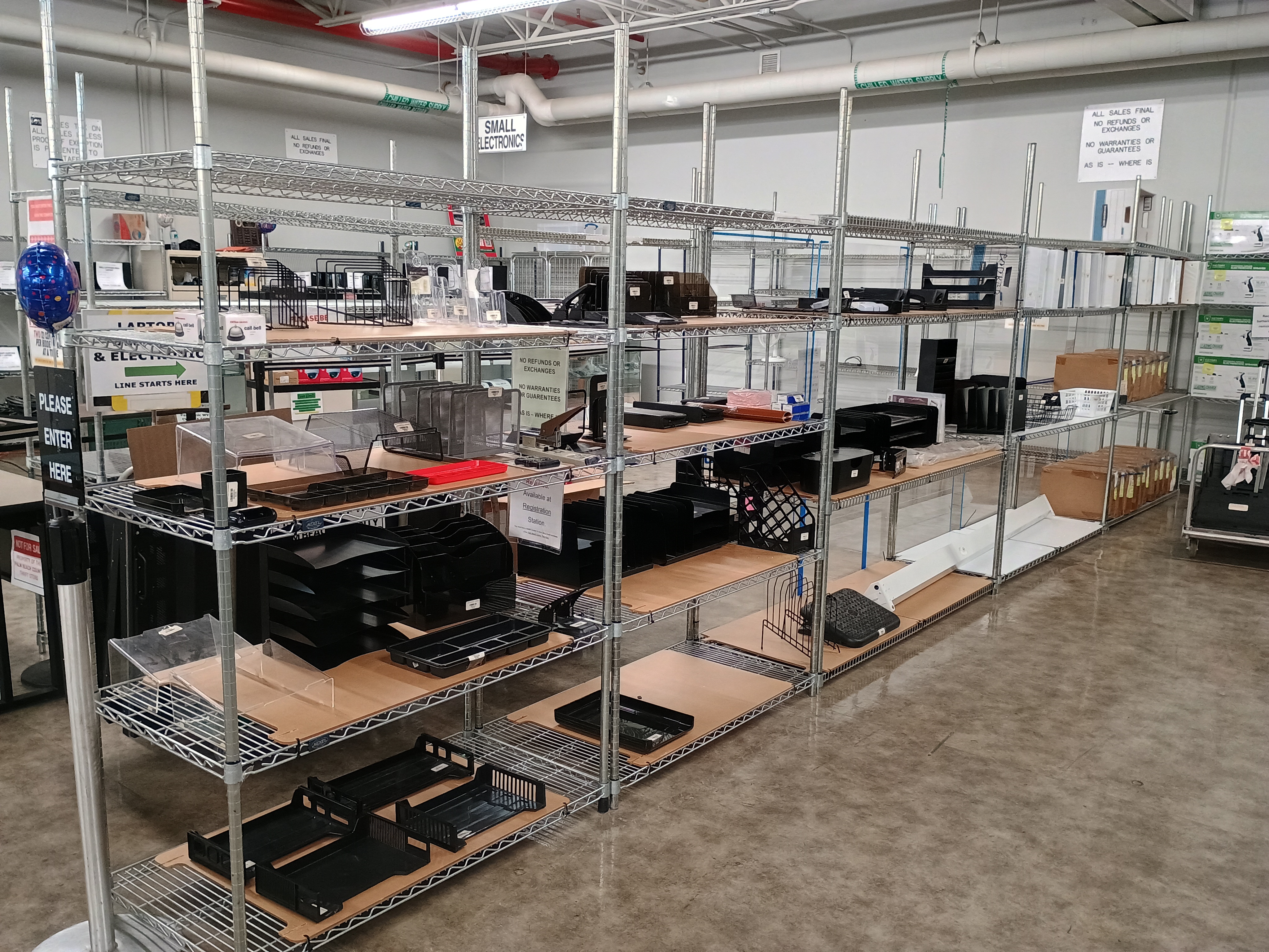 Metal wire racks with various merchandise, office supplies and boxes of pens.jpg